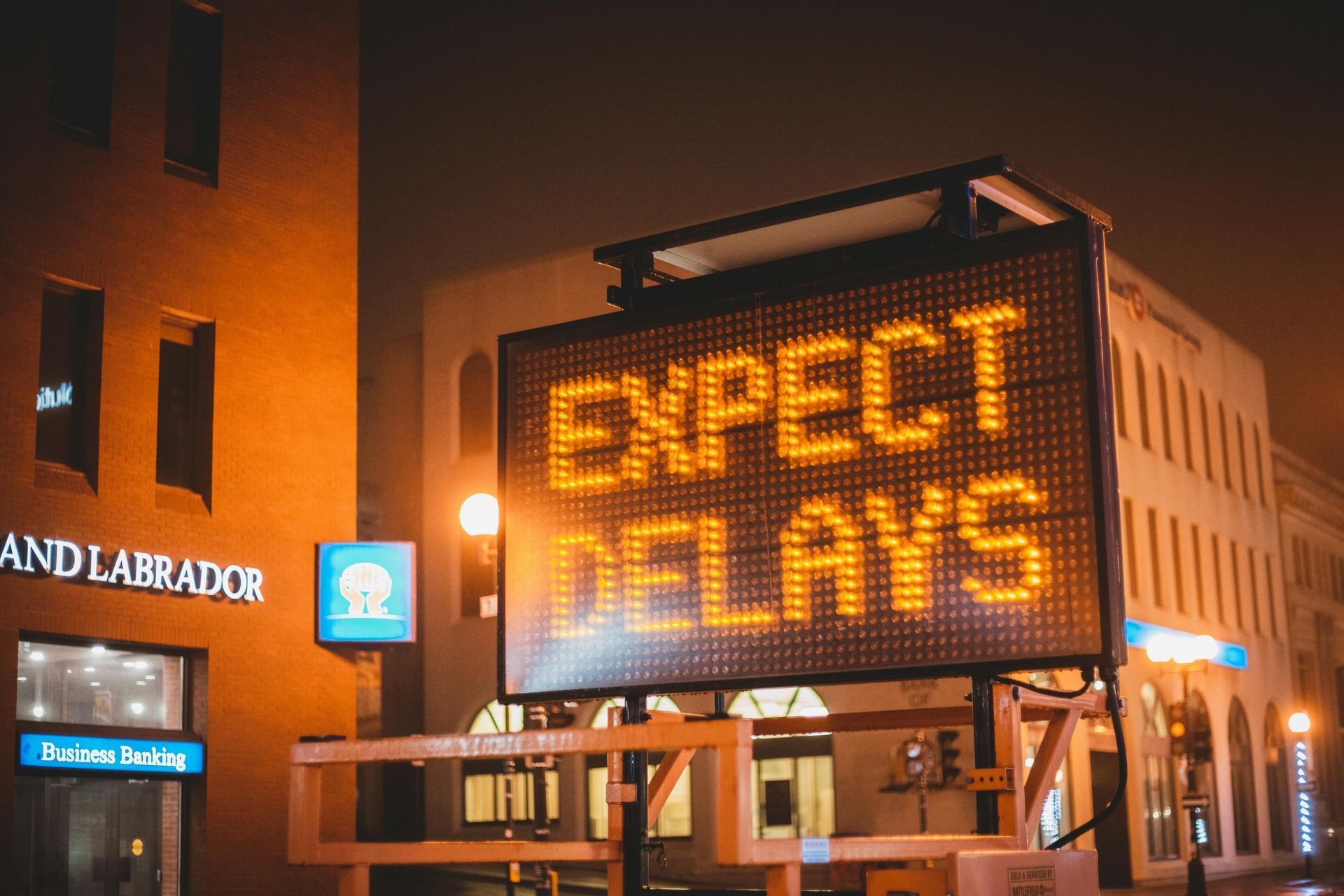 Neon “Expect Delays” road sign symbolizing construction and equipment delays in Hawaiʻi projects.