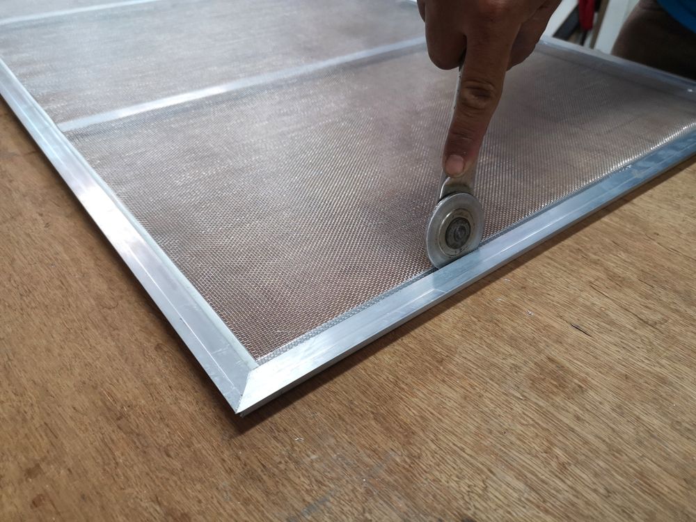 Person Using a Roller Tool to Install Screen Mesh Into a Window Frame — All Security Screens & Repairs In Bungalow, QLD