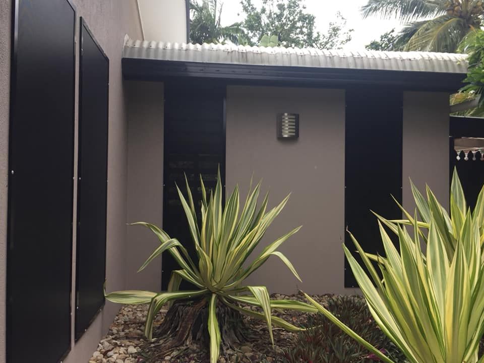 Exterior Building With Black Panels, Beige Walls, Small Roof, and Plants — All Security Screens & Repairs In Bungalow, QLD