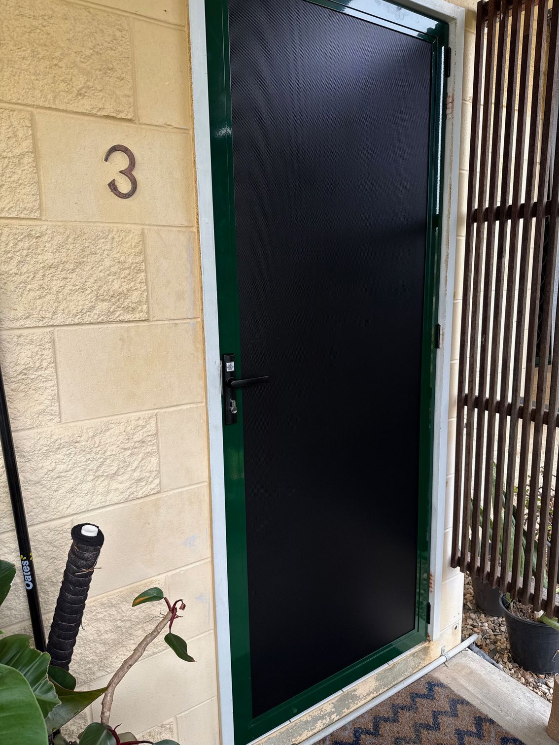 Black Screen Door With Green Frame, Number 3 on the Wall, and a Doormat — All Security Screens & Repairs In Bungalow, QLD