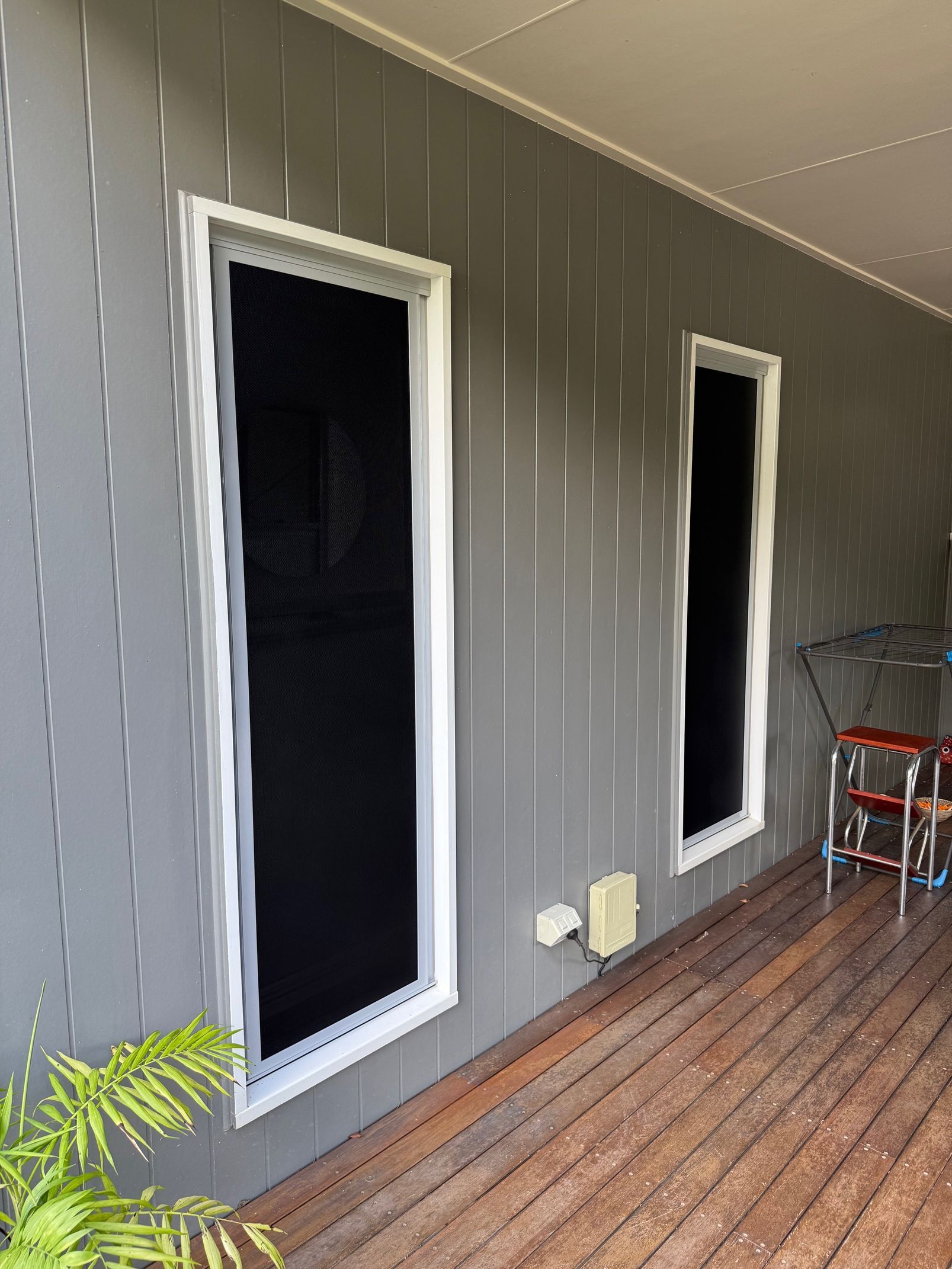 Two Windows With Black Screens on a Grey Wall — All Security Screens & Repairs In Bungalow, QLD