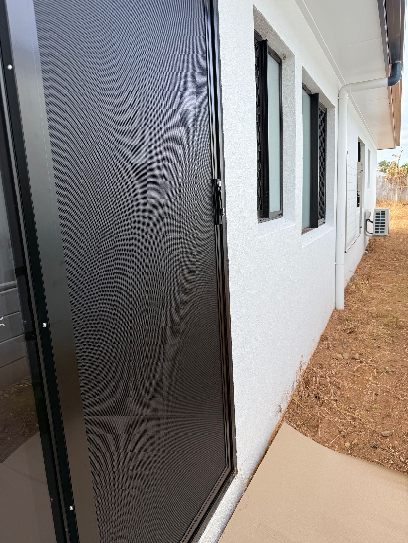 Black Security Door With Patterned Mesh on a White Building — All Security Screens & Repairs In Bungalow, QLD