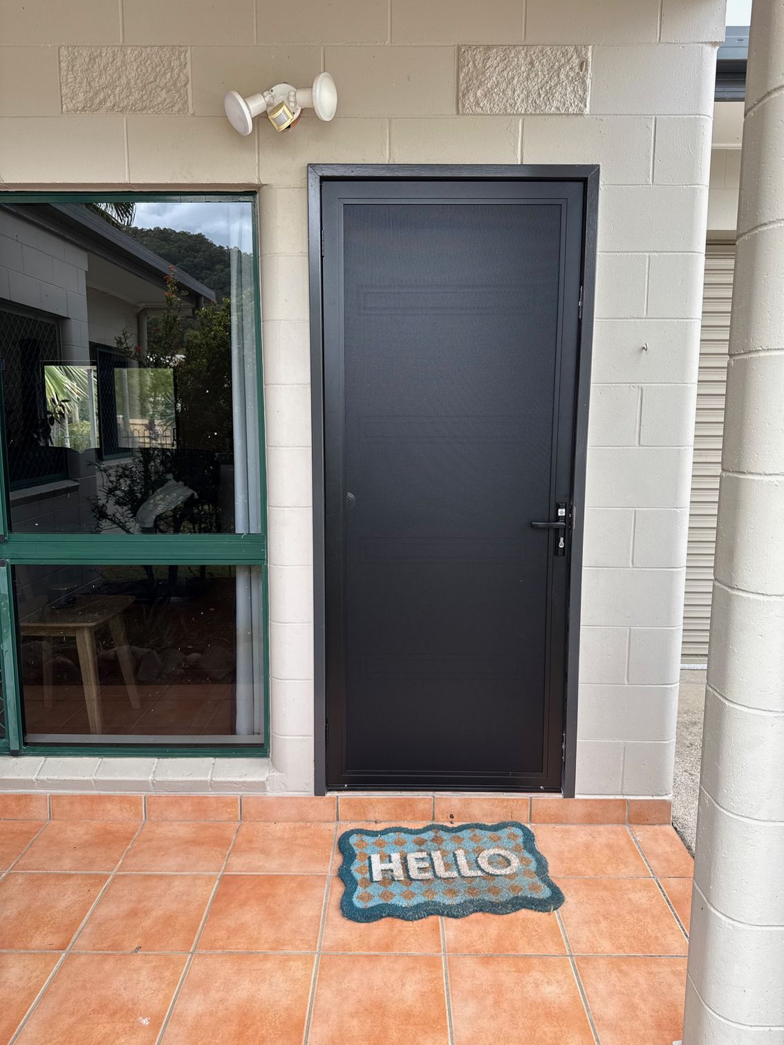 Black Door With Hello Doormat on a Brick Patio — All Security Screens & Repairs In Bungalow, QLD