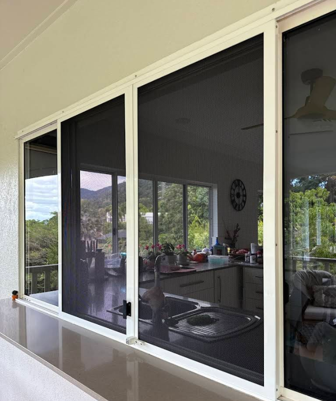 Close-up of a window screen with a blurred green and white outdoor view — All Security Screens & Repairs In Bungalow, QLD