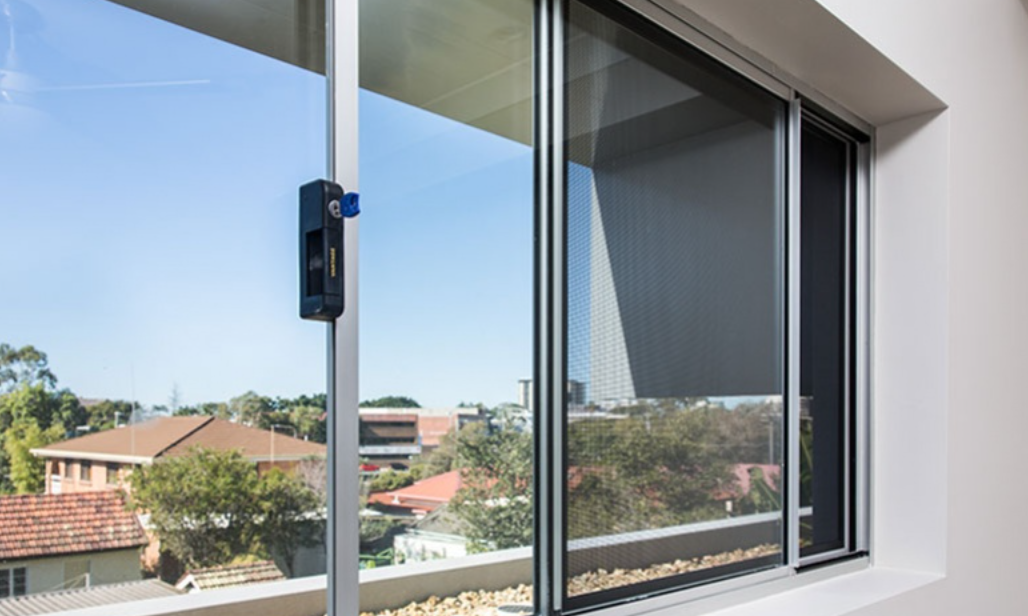 Young Girl Looking Out a Window With a Toy, Leaning on a Bed in a Bedroom — All Security Screens & Repairs In Bungalow, QLD