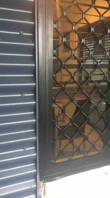 Black Security Door With Diamond Pattern and Dark Corrugated Siding — All Security Screens & Repairs In Bungalow, QLD