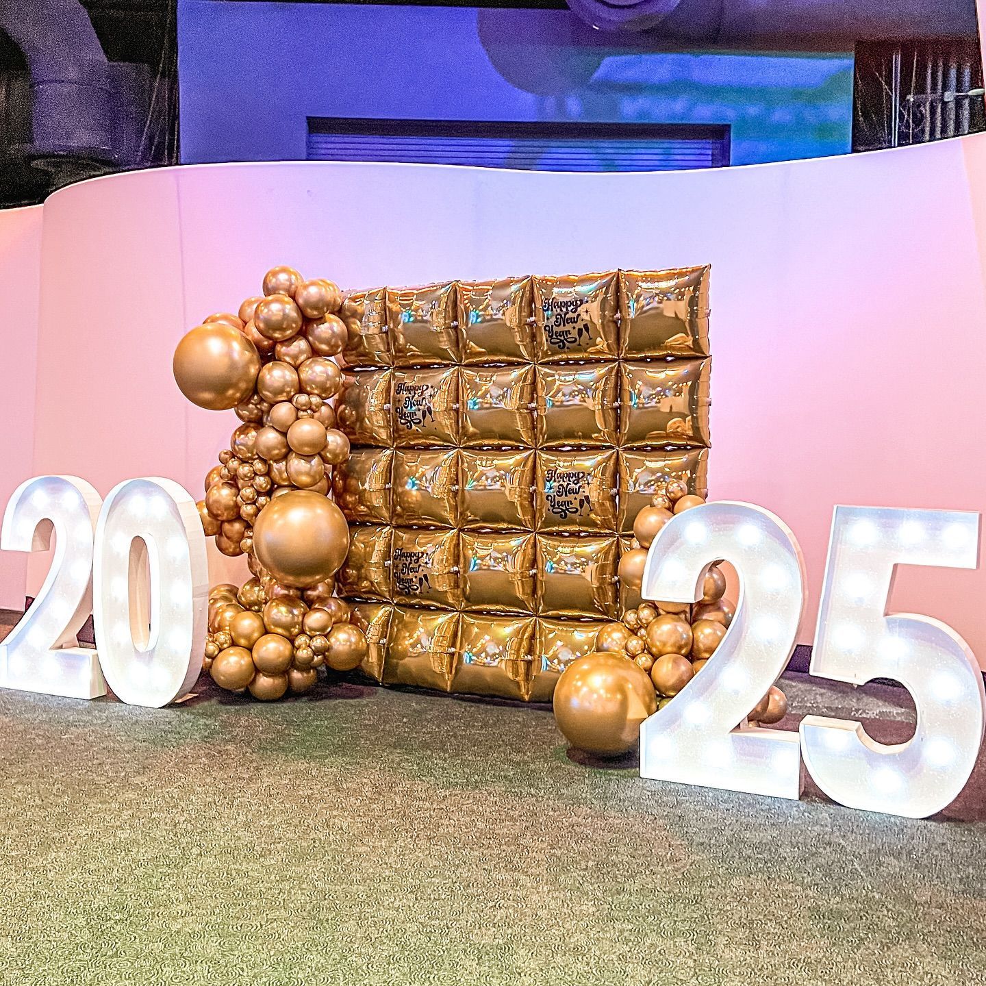 Gold balloons and 2025 illuminated numbers decorate a celebratory backdrop.