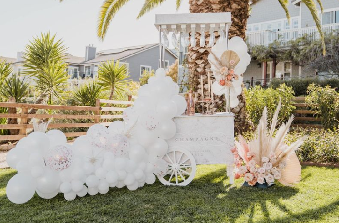 a cart filled with balloons and flowers is sitting in the grass .