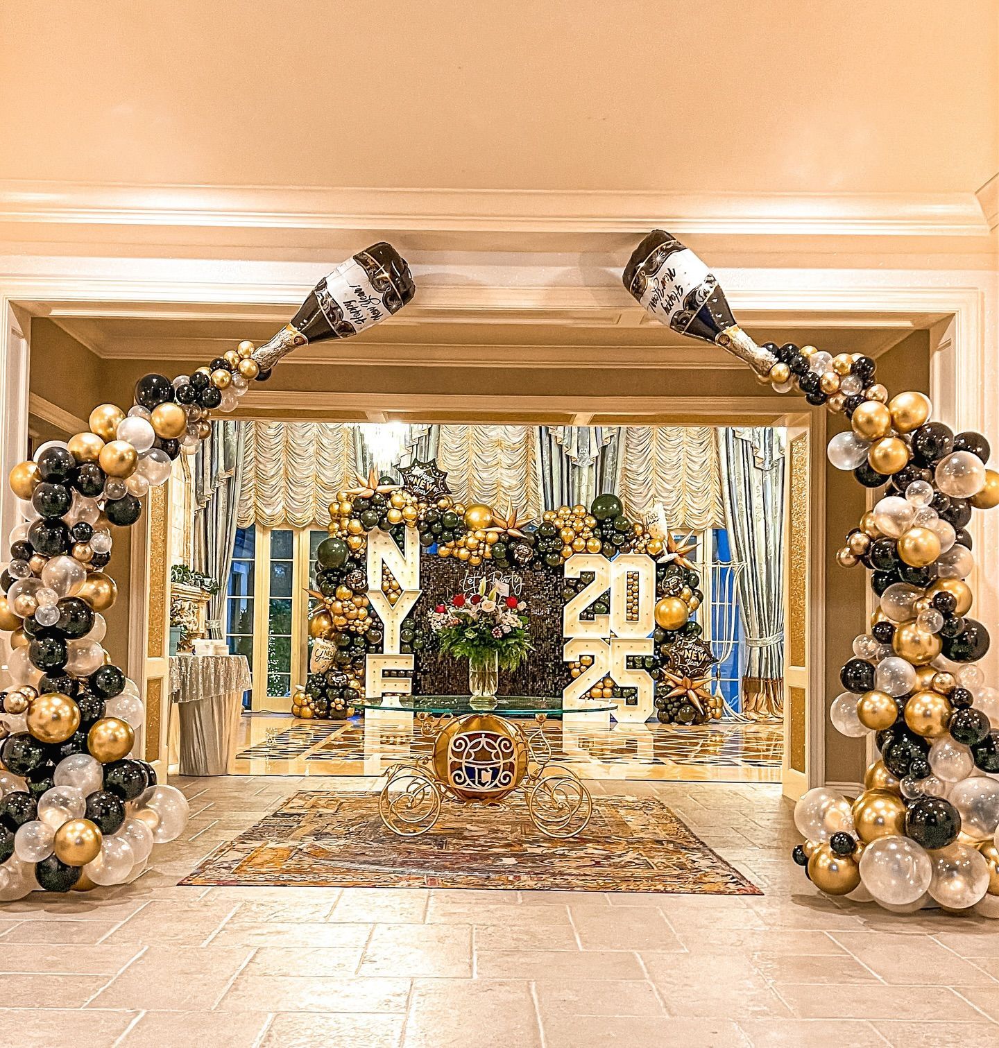 New Year's Eve party entrance with gold, black, and silver balloon arch, and 2025 display.