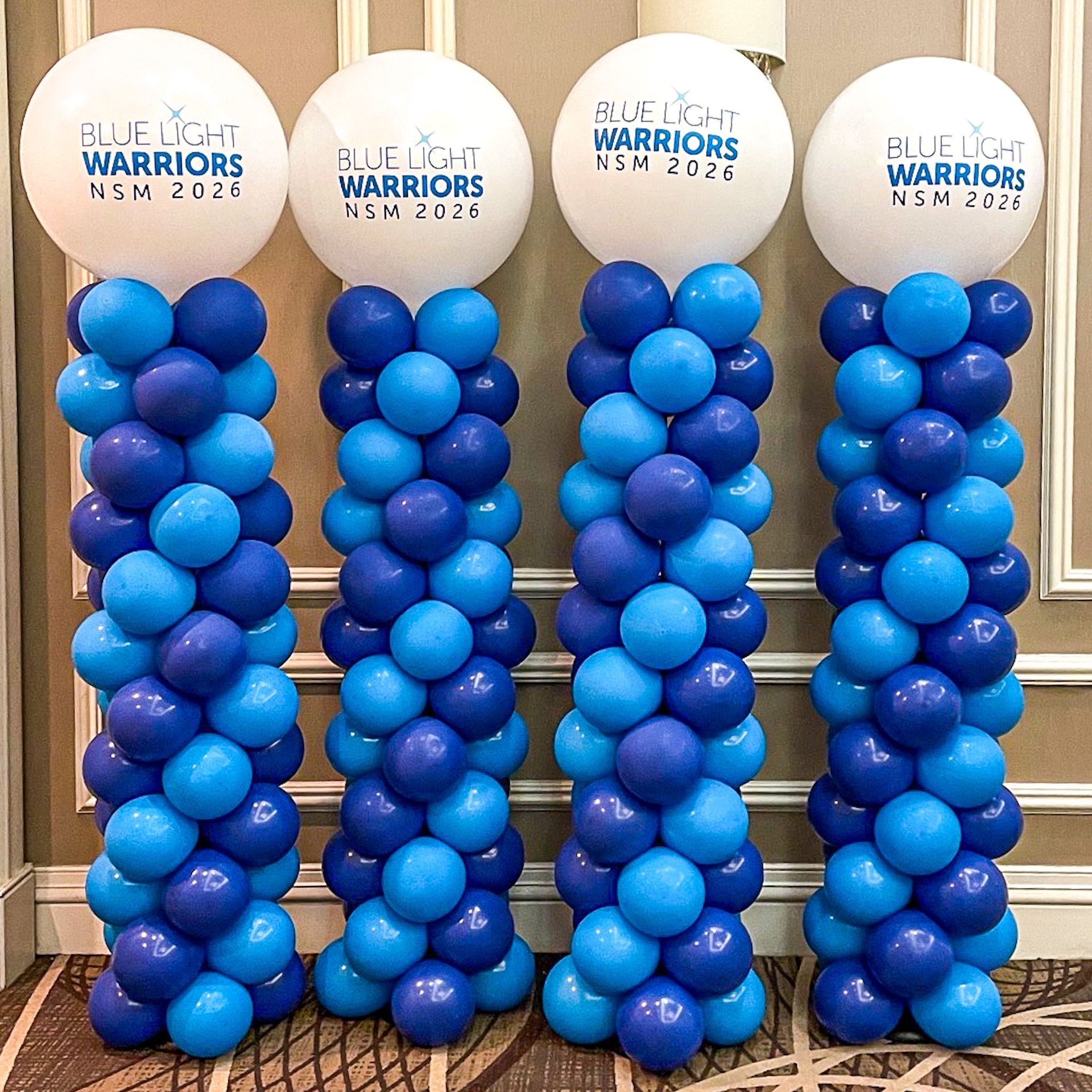 Four blue and white balloon columns; each with a large, printed top balloon.