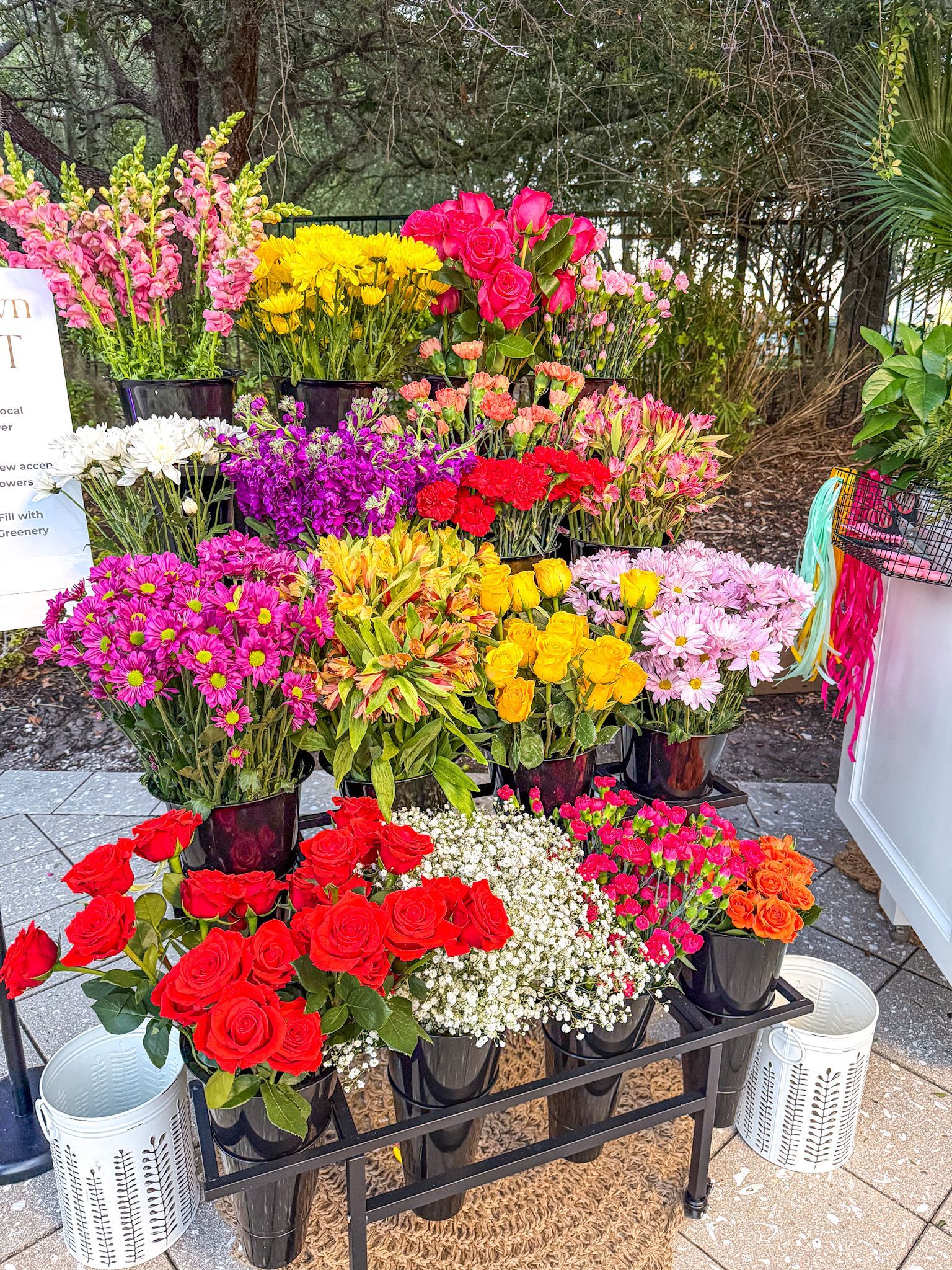 A vibrant flower display with rows of colorful blooms in a market setting.
