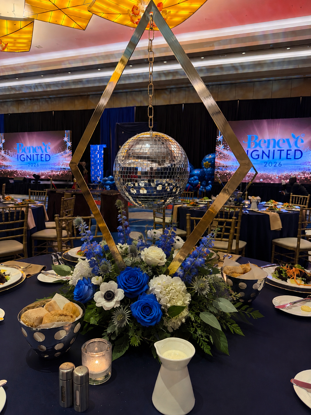 Decorated banquet table with blue flowers, candles, and a mirrored centerpiece at an elegant event venue
