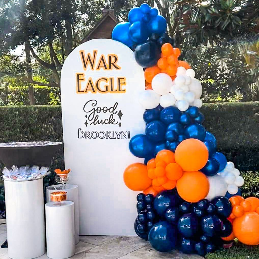 A bunch of blue and orange balloons are sitting on top of a white wall.