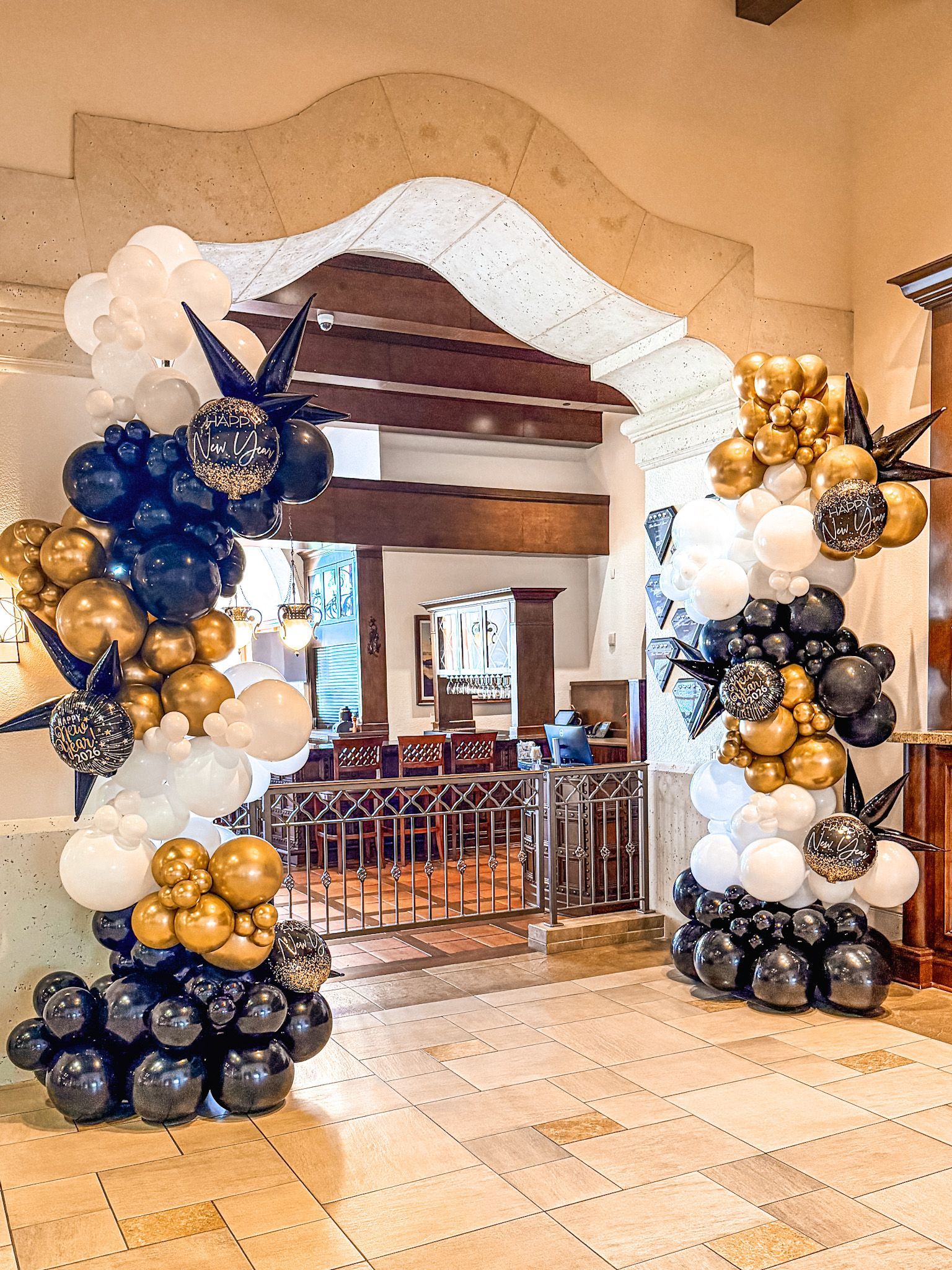Balloon archway in black, gold, and white at an event entrance.