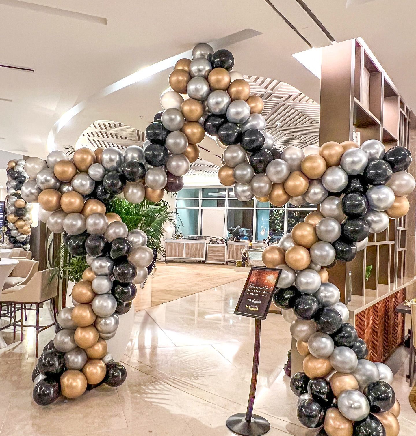 Star-shaped balloon arch in gold, silver, and black, framing an entrance.