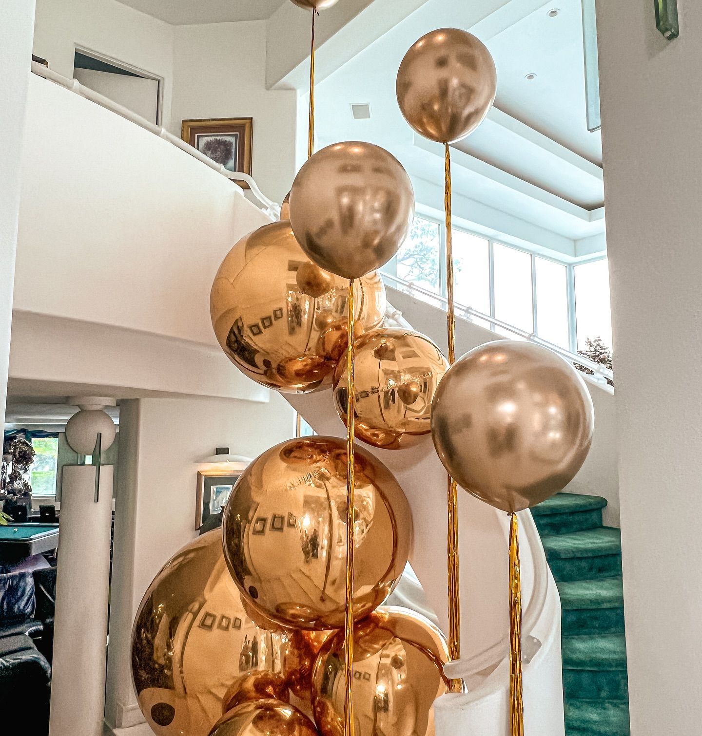 A bunch of gold balloons are hanging from a staircase