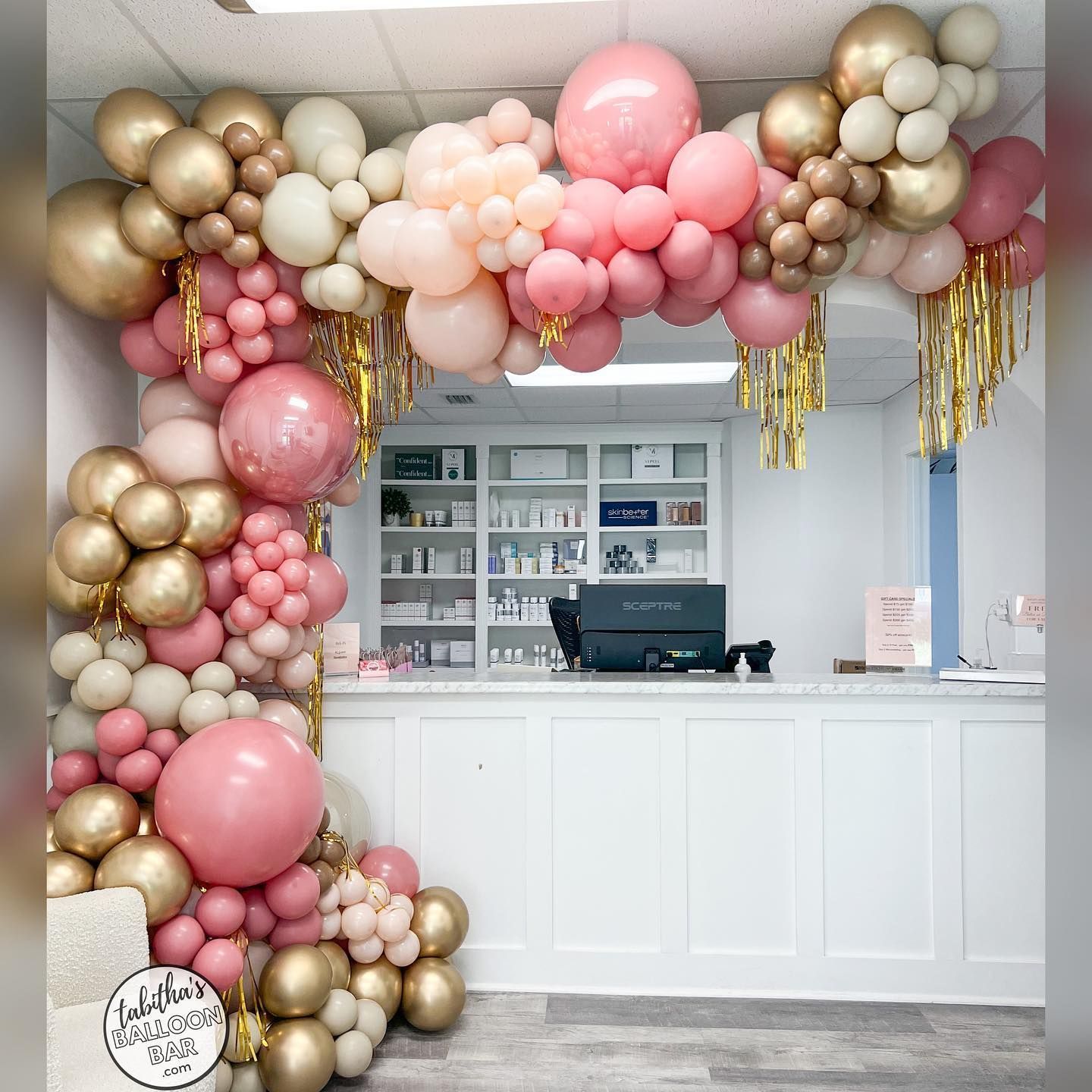 A bunch of pink and gold balloons are hanging from the ceiling
