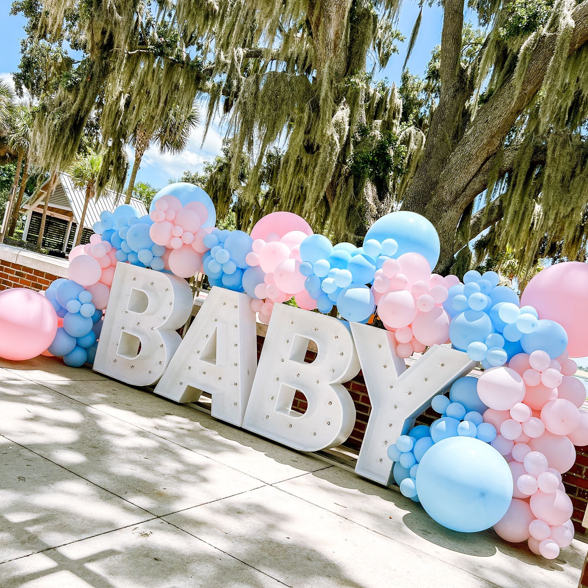The word baby is surrounded by pink and blue balloons.