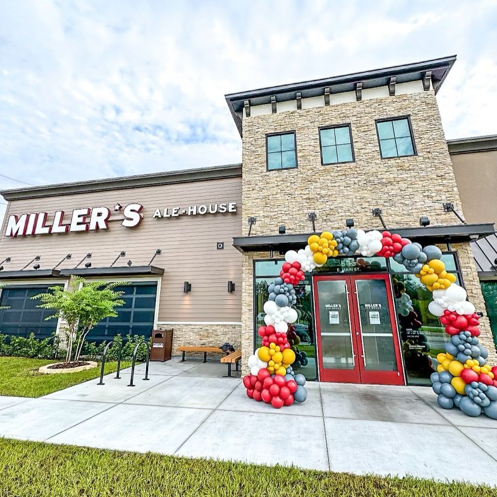 Miller's Ale House restaurant with a balloon arch over the entrance. Exterior view, gray and red balloons.