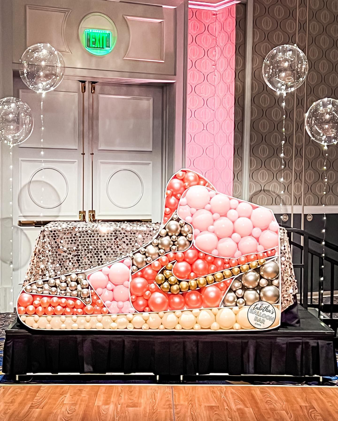 A bed made of balloons is sitting on a stage in a room.