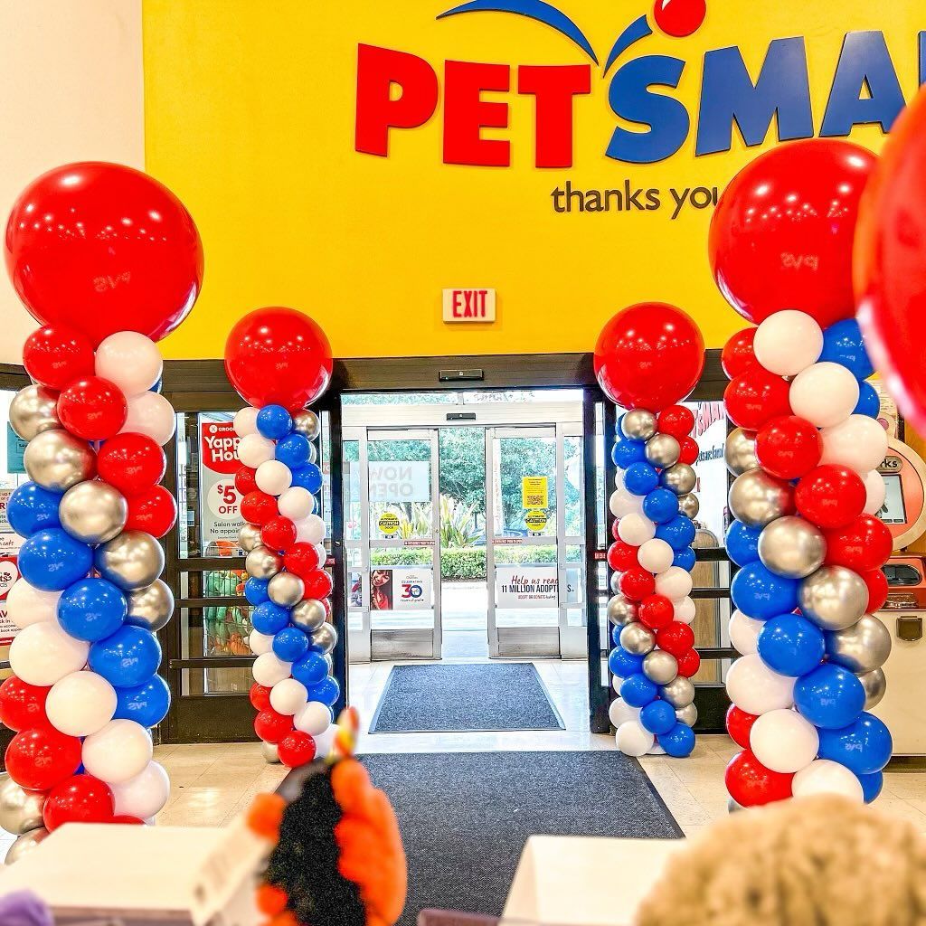 PetSmart entrance decorated with red, white, blue, and silver balloon columns and a large red balloon at the top.