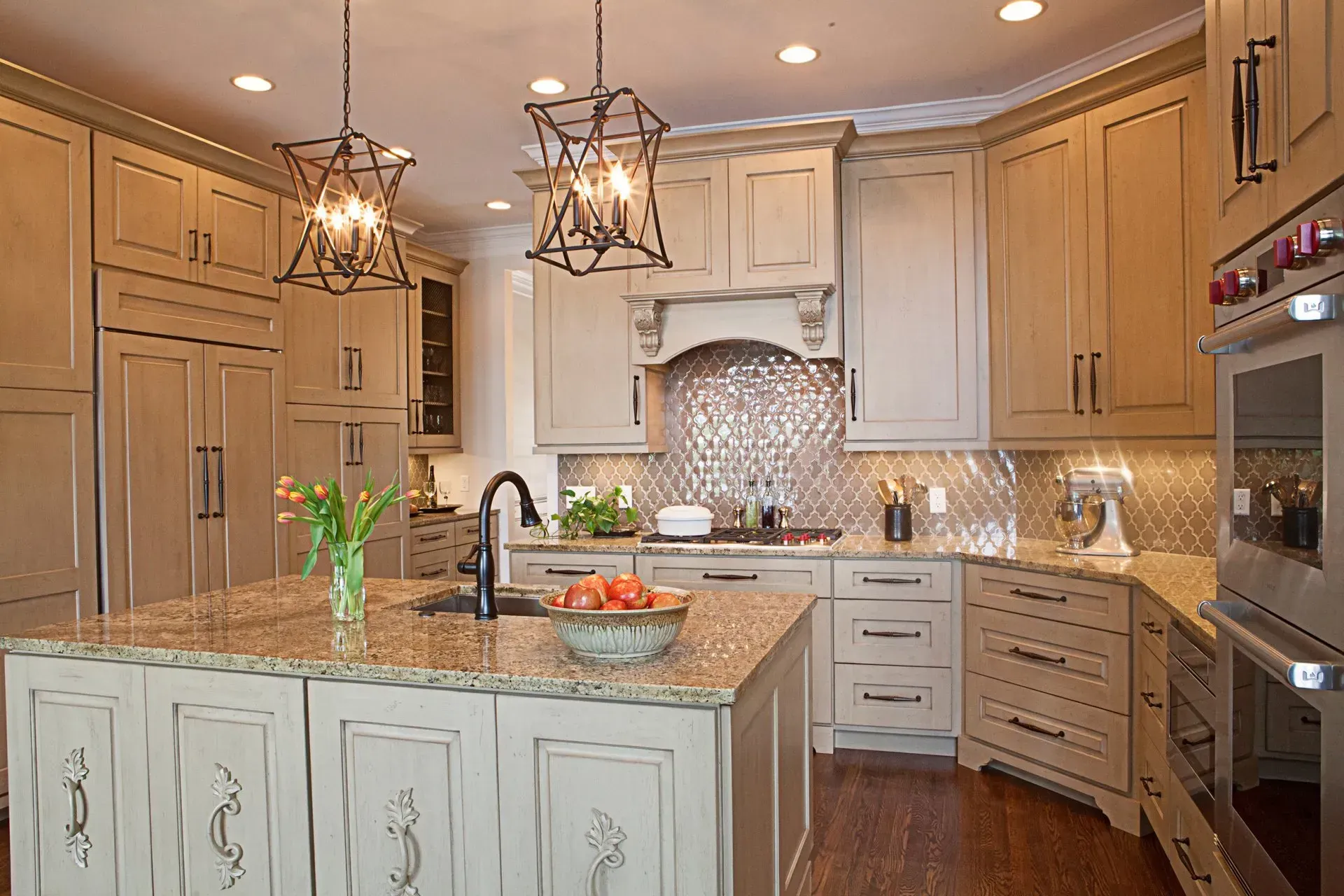 Elegant kitchen with light-colored cabinets, granite countertops, and decorative light fixtures.