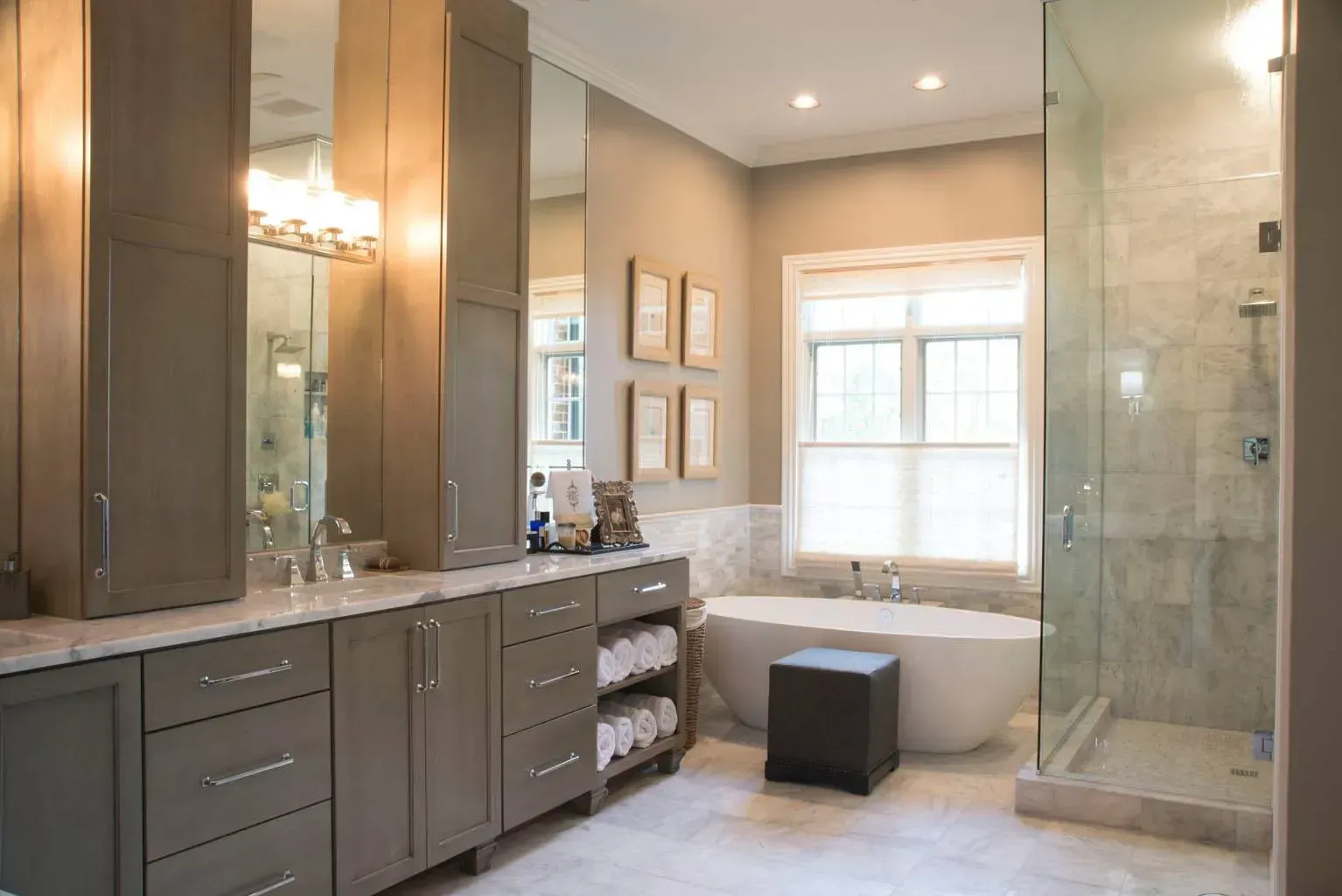 Bathroom with gray cabinets, large mirror, soaking tub, and glass shower.