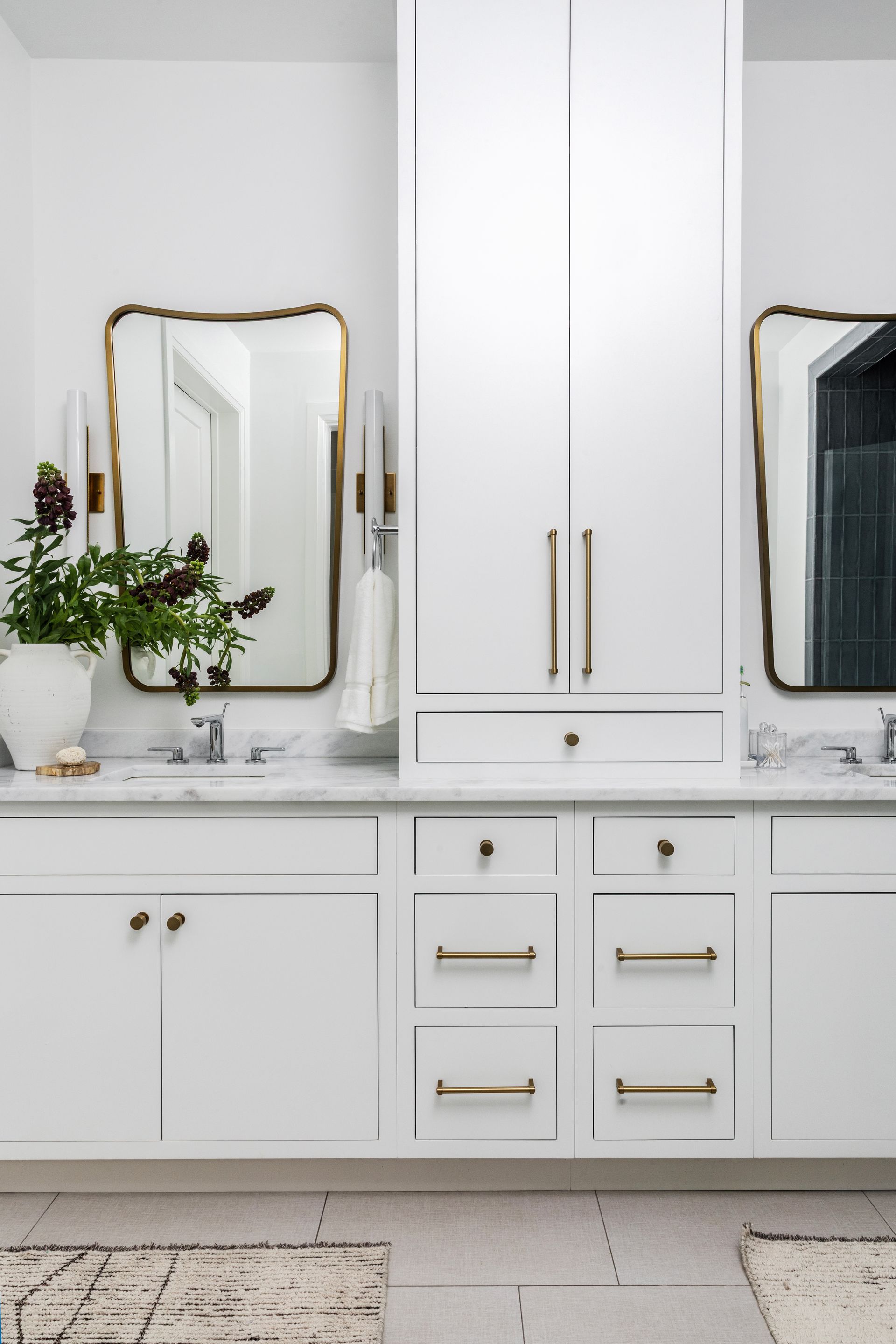 White bathroom with gold-framed mirrors, white cabinetry, marble countertop, and gold hardware.