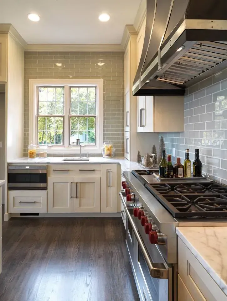 Kitchen with light cabinets, blue tile backsplash, stainless steel range, and dark wood floor.
