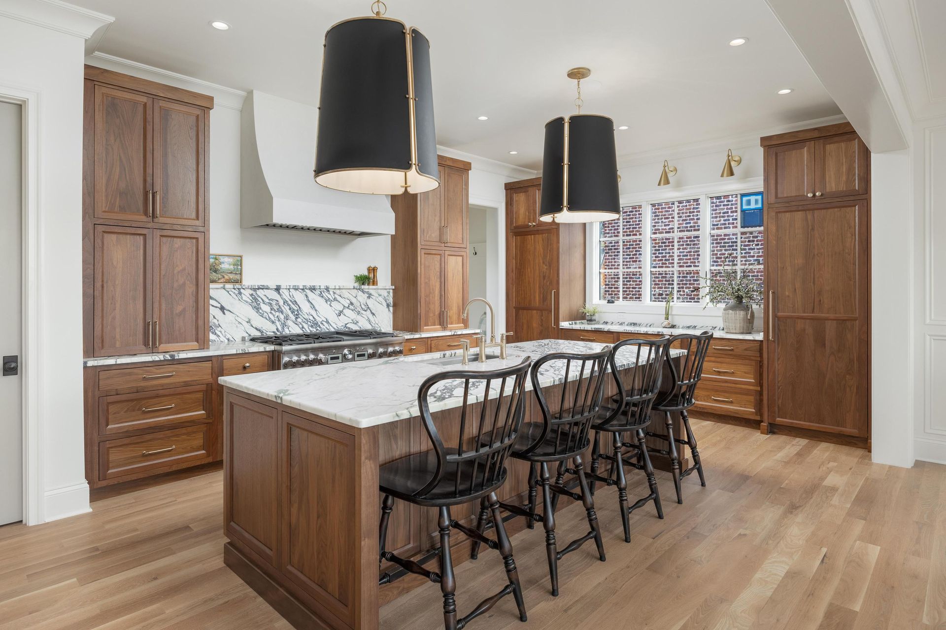 Spacious kitchen with wood cabinets, marble countertops, island with seating, pendant lights.