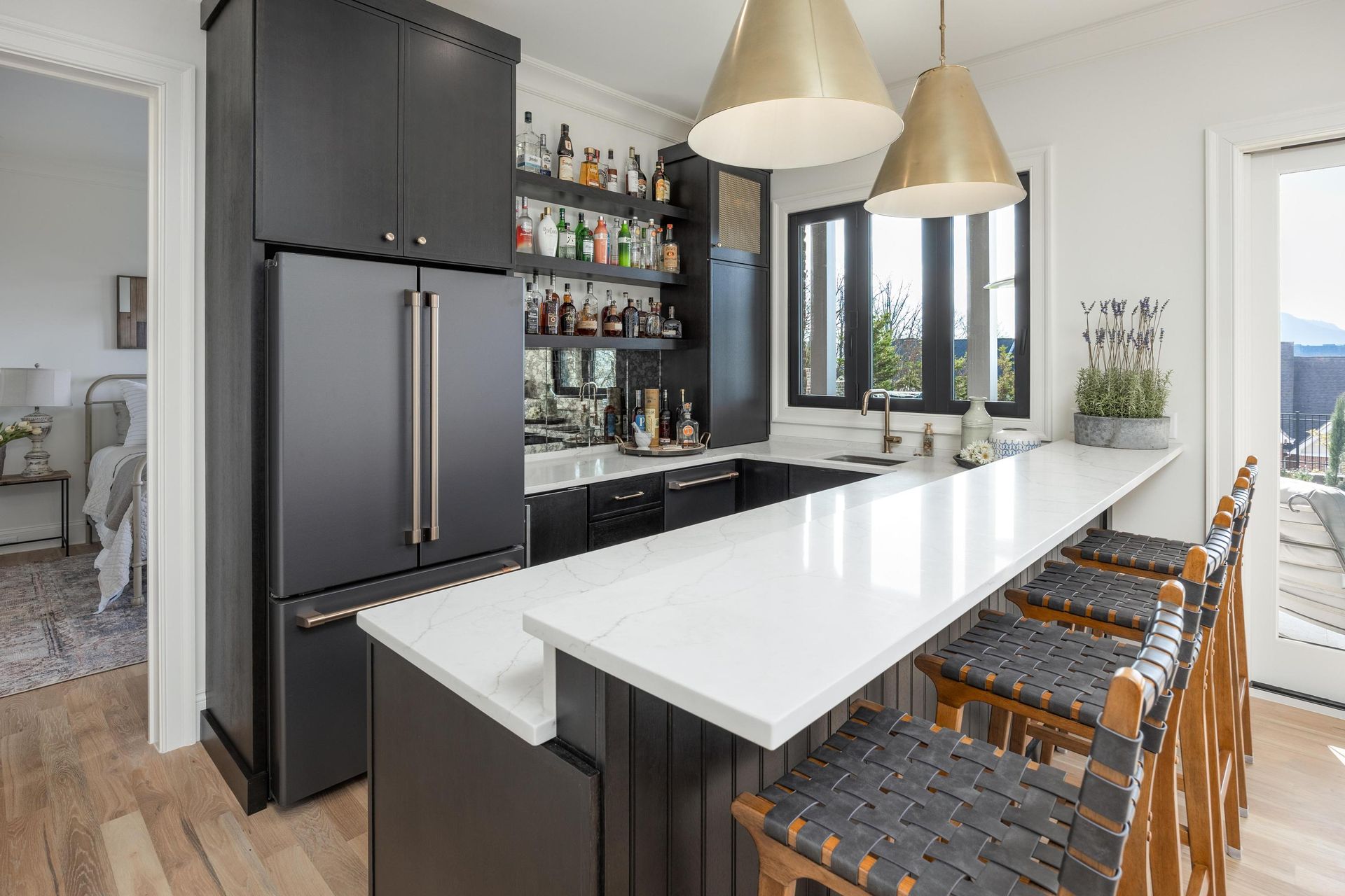 Kitchen bar with dark cabinets, white countertop, and gold pendant lights.