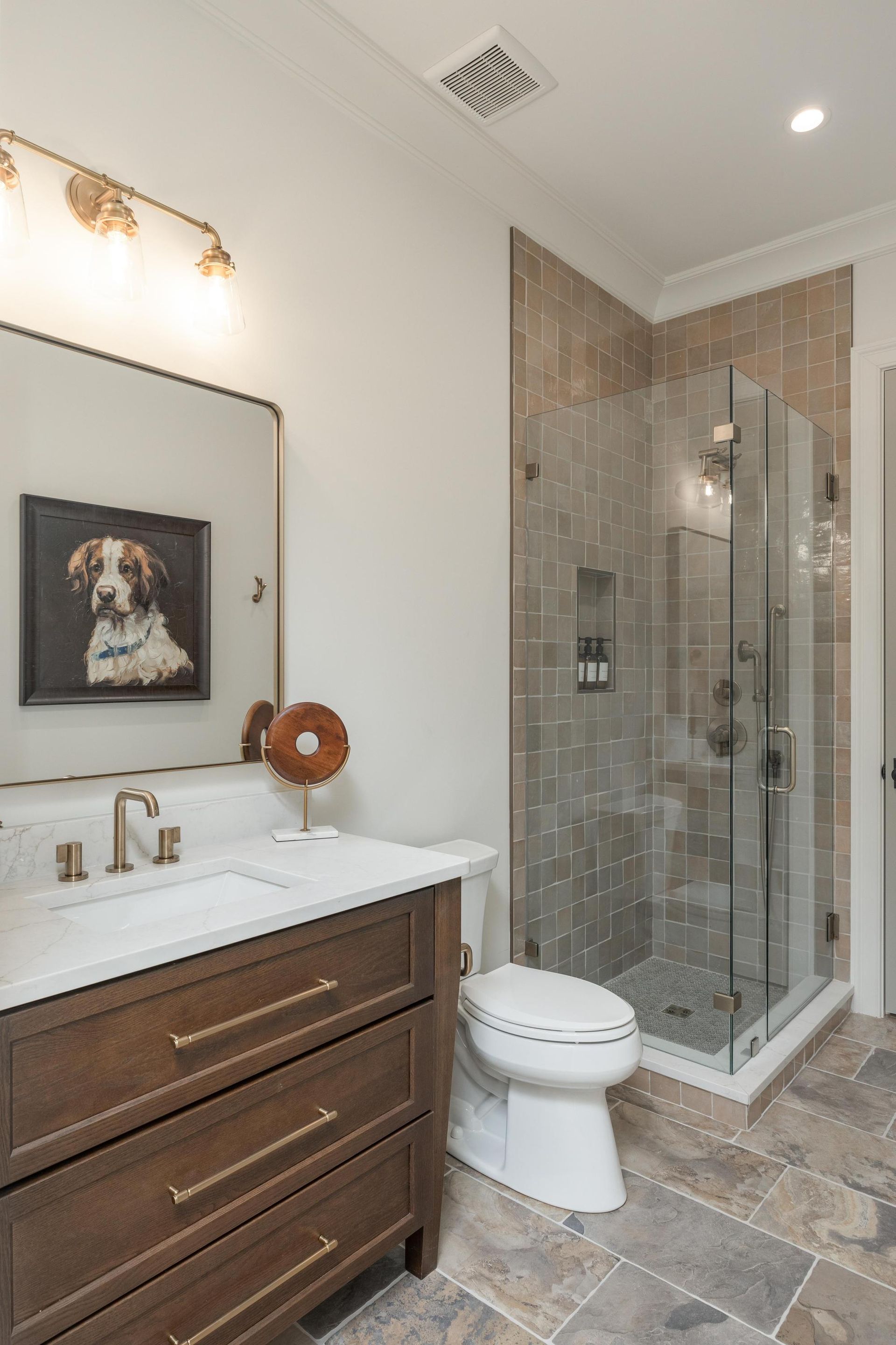 Bathroom with dark wood vanity, glass shower, and patterned tile.