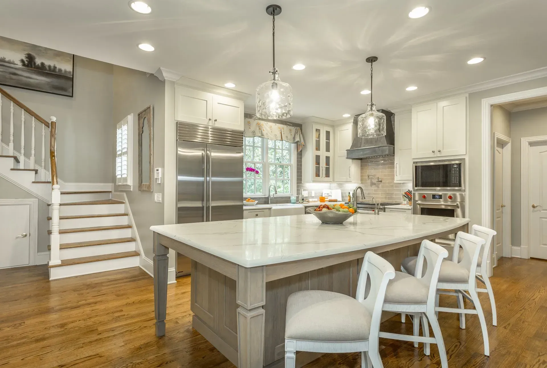 Spacious, bright kitchen with island, stainless steel appliances, and wood flooring.