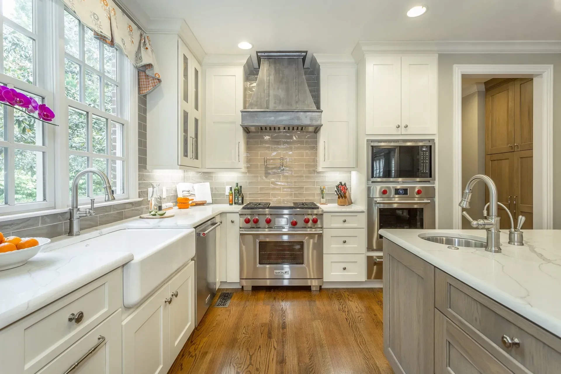 Bright kitchen with white cabinets, stainless steel appliances, and a light gray island.