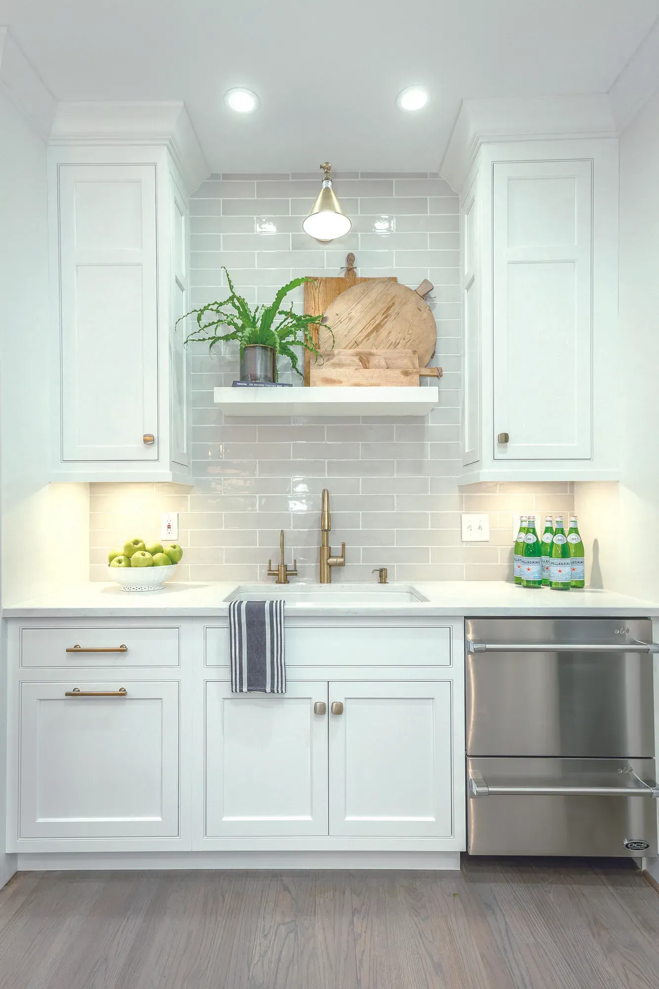 White kitchenette with cabinets, subway tile backsplash, sink, and dishwasher.