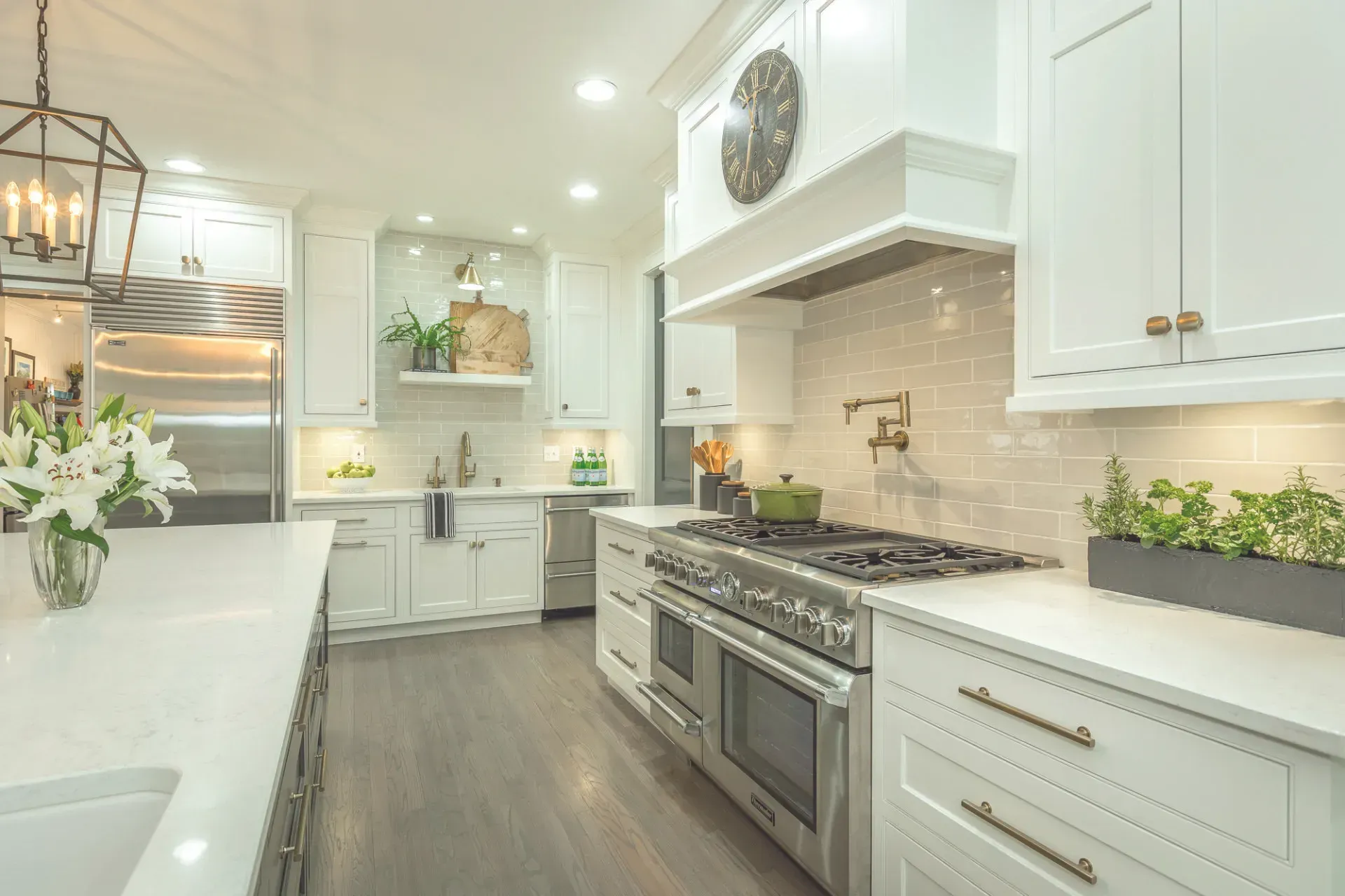 White kitchen with stainless steel appliances, white cabinets, and wooden floors.