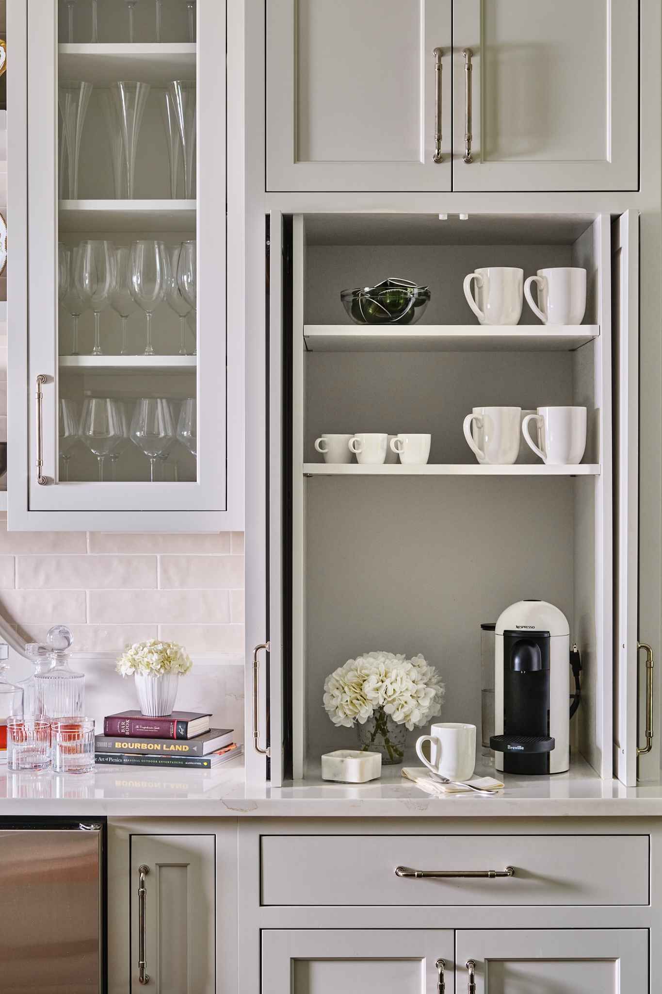 Kitchen cabinet with open storage for coffee maker, cups, and dishware. White and gray tones.