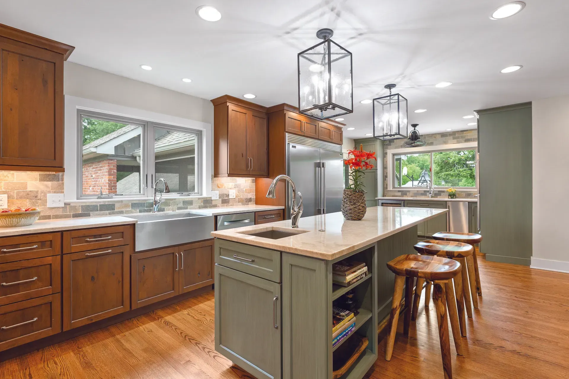 Kitchen with wooden cabinets, green island, stainless steel appliances, and wood flooring.