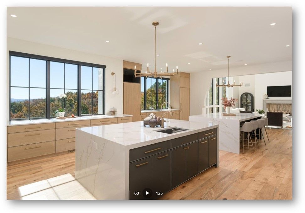 Modern kitchen with large island, natural light, and a view of trees.