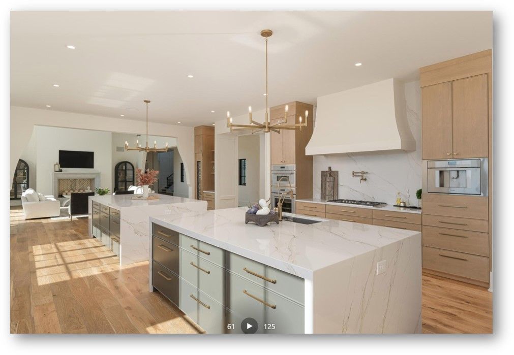 Modern kitchen with two islands, light wood cabinets, and marble countertops.