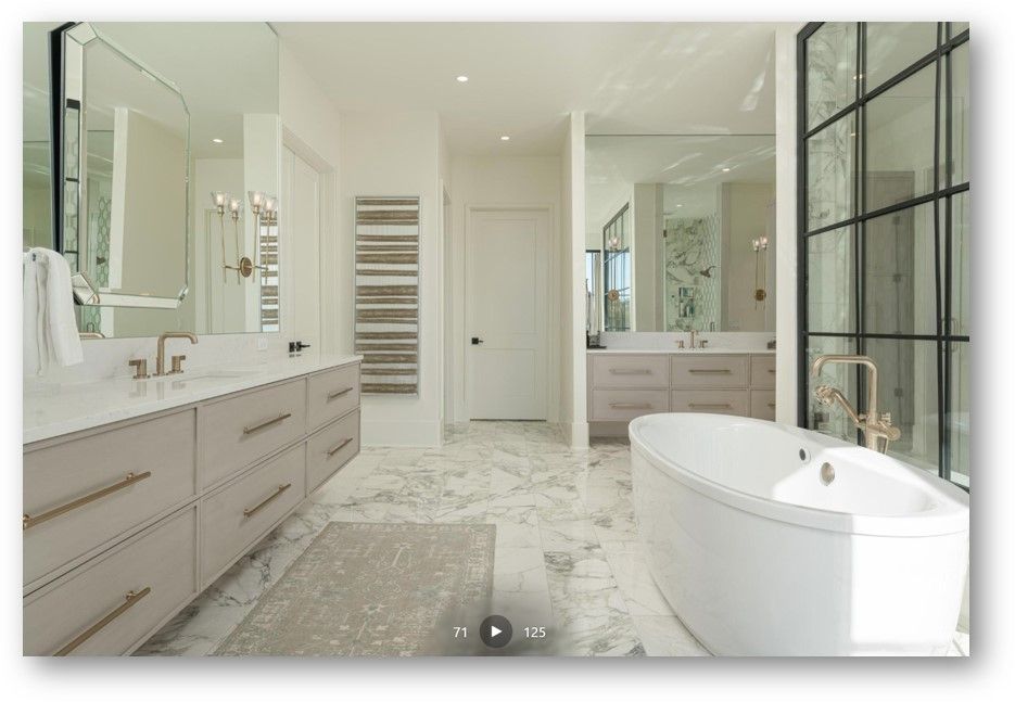Luxurious modern bathroom: light wood cabinets, marble floors, freestanding tub, large mirrors, glass shower, neutral colors.