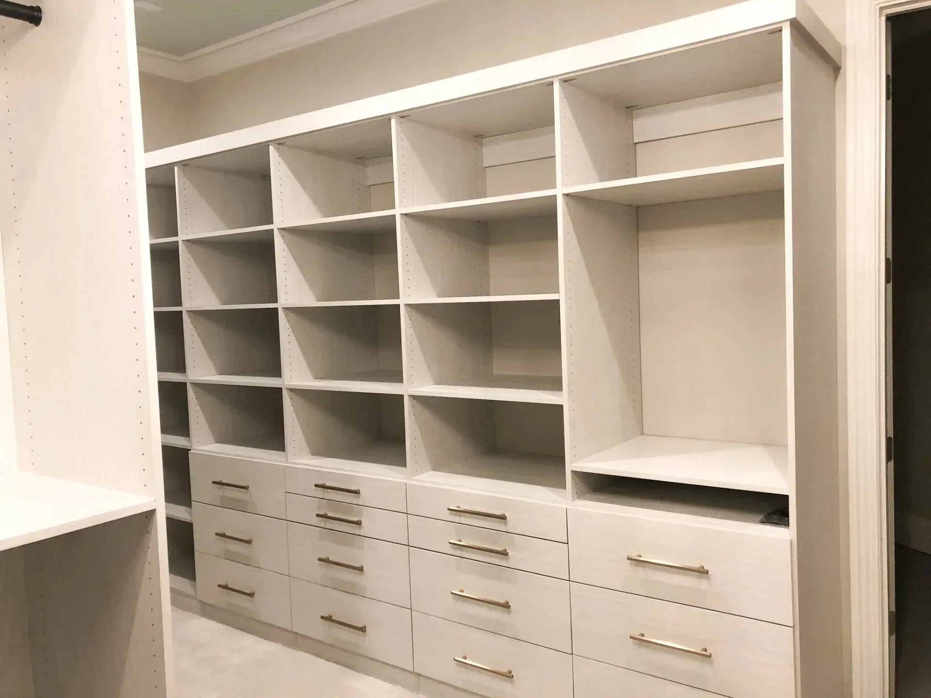 White closet shelving unit with drawers and open shelves.
