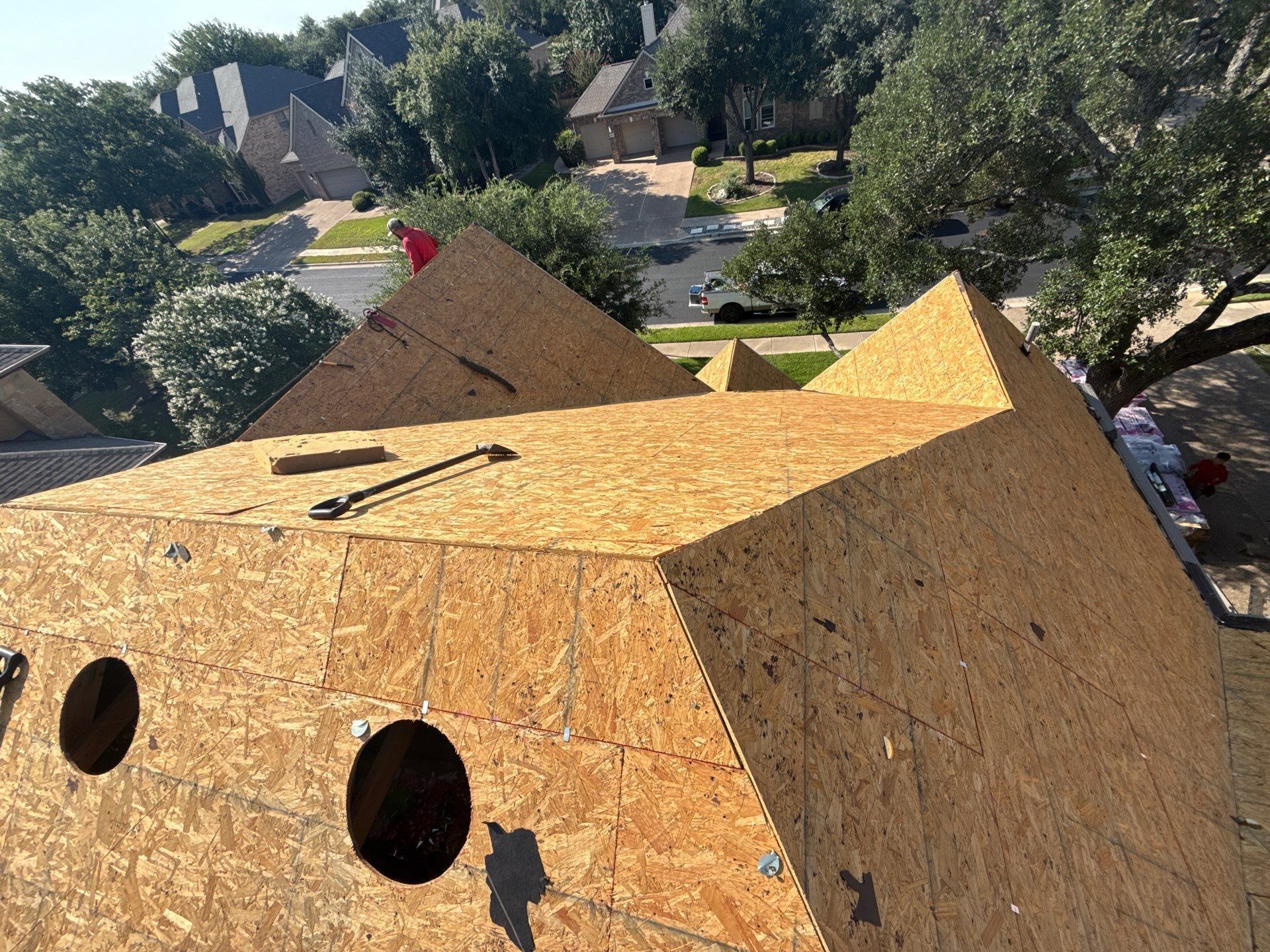 OSB sheathing on a multi-faceted roof with two circular vent holes, prepared for shingles.