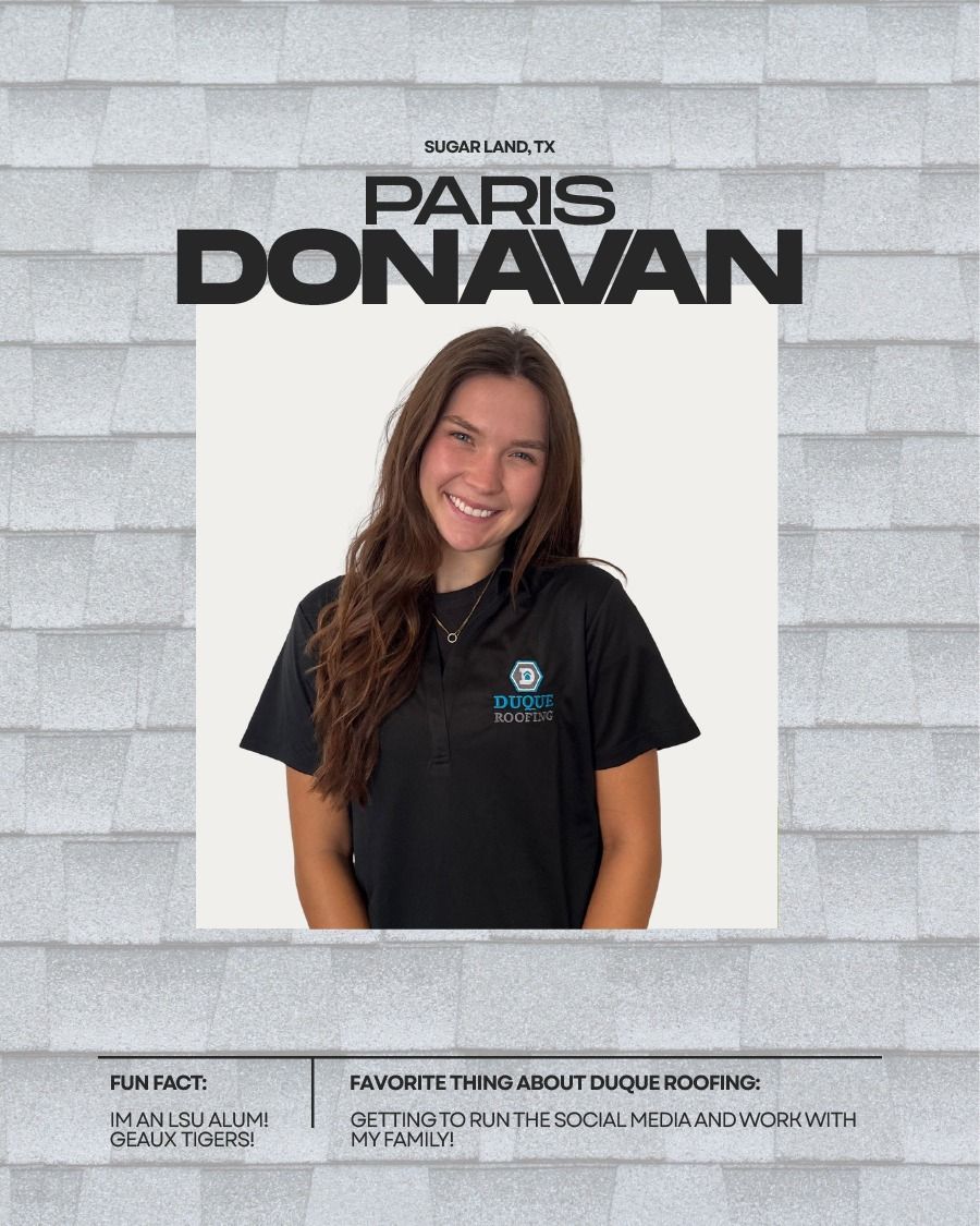 Paris Donavan smiling, wearing a black shirt, in front of a white background and grey textured roof.