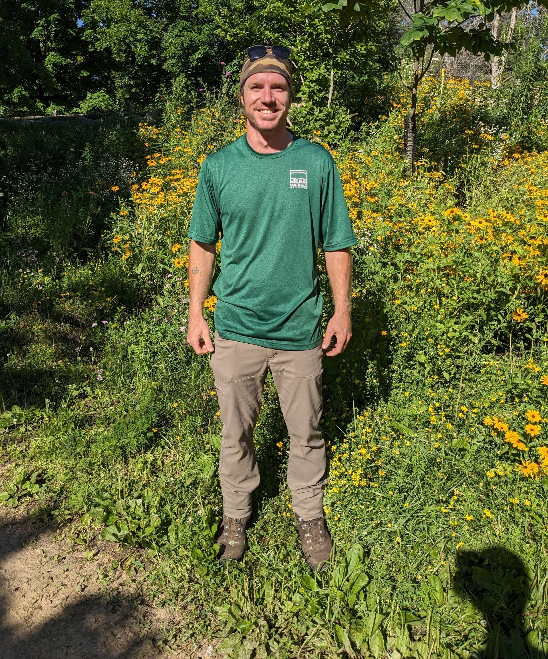 A man with a green shirt and yellow prairie flowers in background