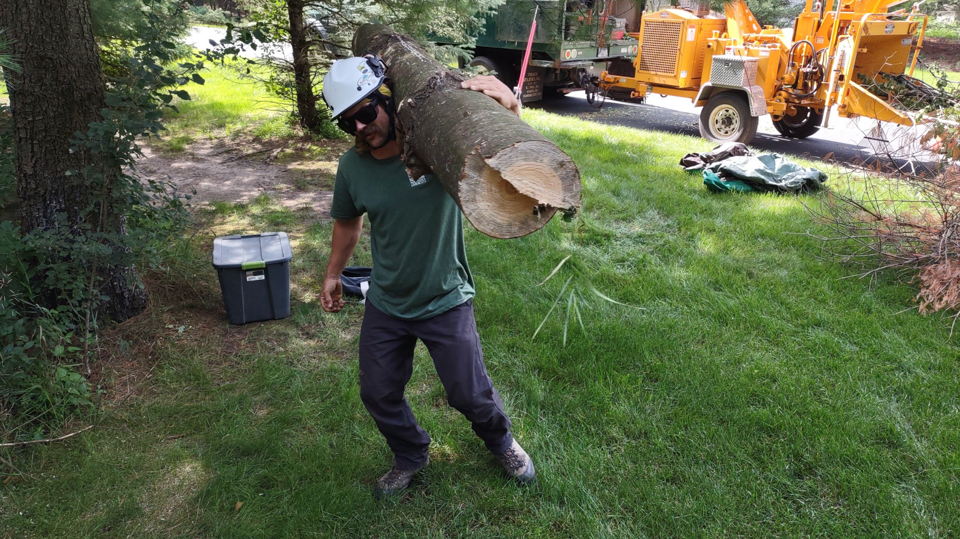 A man is carrying a large tree stump on his back.