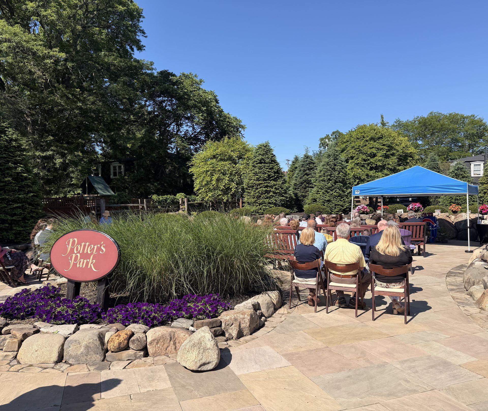 A group of people are sitting at tables under umbrellas on a patio.