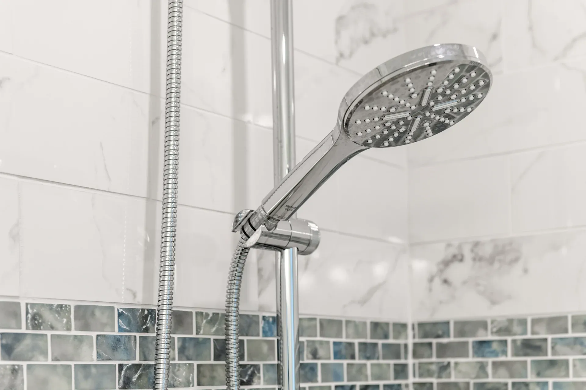 Showerhead in a bathroom with marble tile walls.