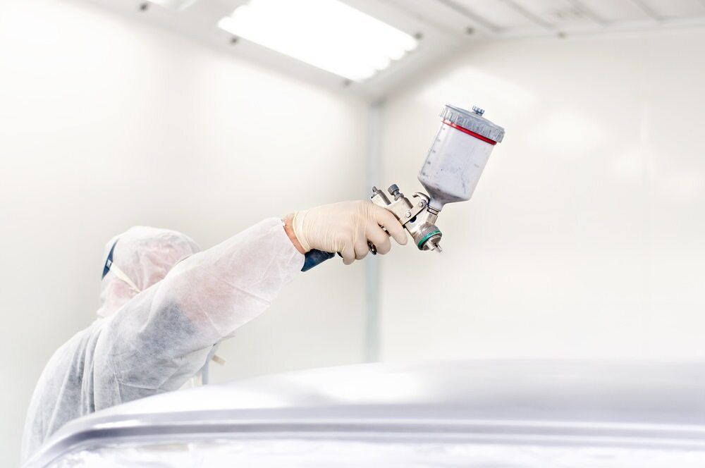 A Man is Painting a Car in a Paint Booth — Stengels Crash Repairs In Garbutt, QLD