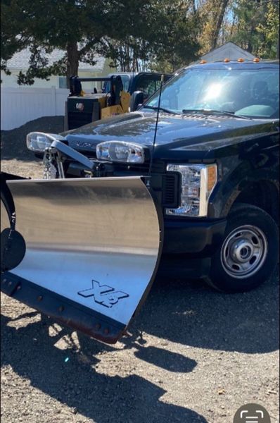 Black pickup truck with snowplow, parked outside.